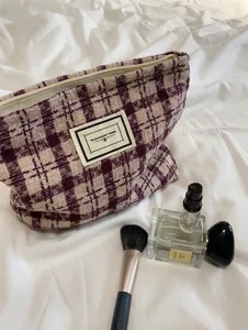Detail of checkered tweed cosmetic bag featuring a Pleasant Time label and zipper