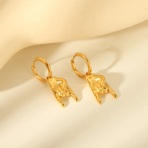 Macro view of gold punk rock hand gesture charm on polished stainless steel hoop earring