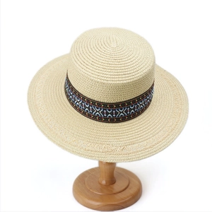 Detail of bohemian woven band with geometric patterns on a flat top straw sun hat