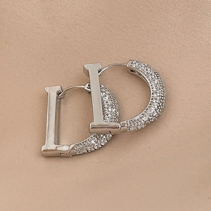Detailed macro view of silver D-letter earrings with shimmering pave-set zircon crystals