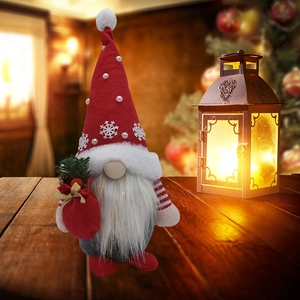 Nain de Noël rouge et gris en peluche posé sur une table en bois décorative chaleureuse