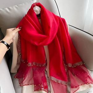 Close-up of red silk scarf with gold bead trim and delicate mesh splice detail
