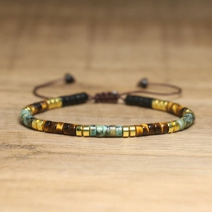 Macro detail of hand-woven bracelet with turquoise, tiger eye beads and gold spacers