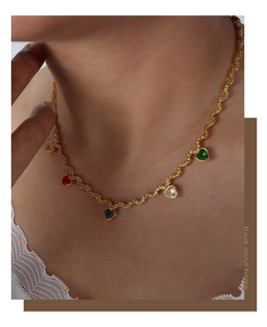 Close-up of gold twist chain necklace featuring five colorful zircon heart pendants on neck
