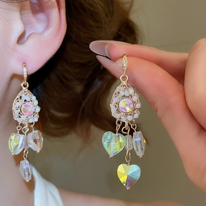 Detail of gold crystal drop earrings with AB rainbow heart tassels and iridescent charms