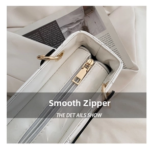 Close-up of golden smooth zipper on white quilted luxury handbag