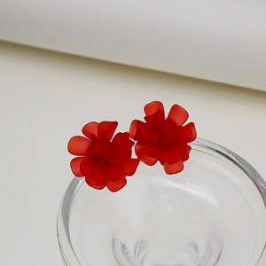 Close-up of matte red flower earrings on a glass rim with 925 silver needles