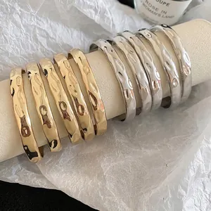 Set of 10 gold and silver hammered metal open bracelets on a professional white display roll