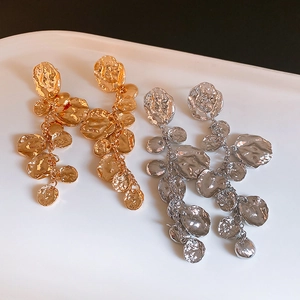 Vue macro de longues boucles d'oreilles à pompons en métal martelé doré et argenté