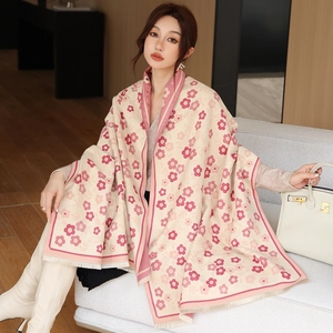 Close-up of beige floral shawl draped on a model, featuring elegant pink flower patterns
