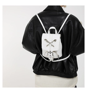Détail d'un mini sac à dos blanc avec découpe papillon et boucle en métal sur un modèle