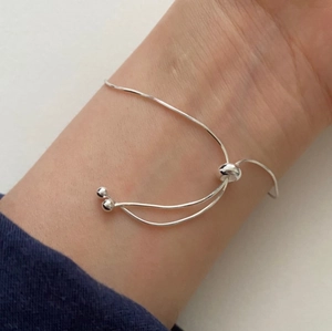 Detail of adjustable silver snake chain bracelet with sliding buckle and round beads