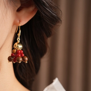 Close-up of Bohemian wood and red glass bead earrings on a model in warm light