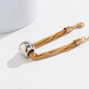 Detailed close-up of multilayer gold chain necklace with a central silver spherical bead