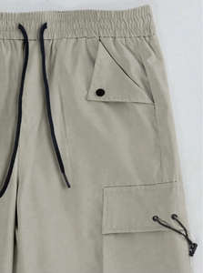 Detail of elastic waist with black drawstring and metal eyelets on khaki cargo pants