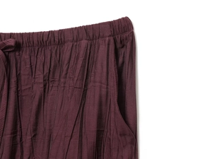 Detail of dark red trousers with elastic waistband, side pockets and vertical crinkle texture