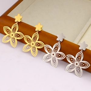 Elegant 18K gold and silver hollow flower earrings displayed on a wooden tray