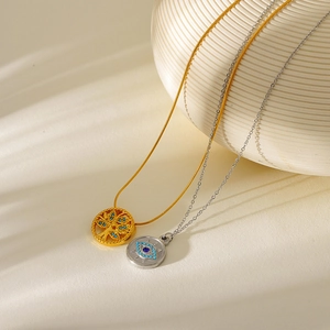 Detail of gold life tree pendant and silver evil eye necklace on ceramic display