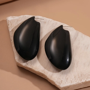 Détail de boucles d'oreilles noires en résine brillante sur un support en pierre