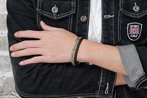 Detail of multi-layered braided men's bracelet with black leather and metallic chain
