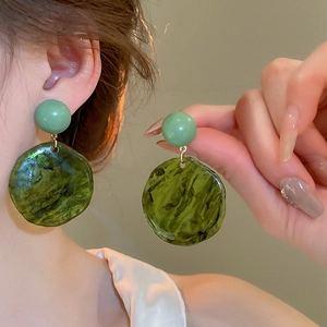 Detail of green resin earrings with marbled texture on model showing elegant fit