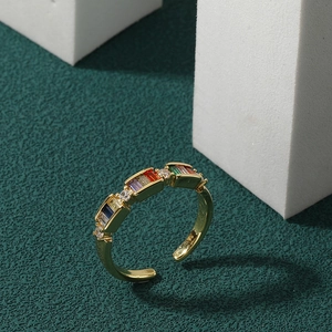 Adjustable gold open ring with colorful zircon gemstones on a textured green base