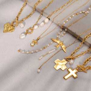 Detalle de collar OT dorado vintage con colgante de corazón y perlas en escalones de piedra
