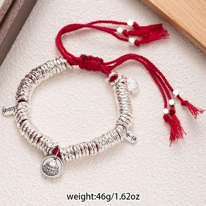 Detail of red braided hand rope with silver beads and lucky charms on white background