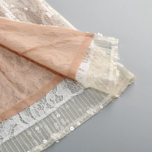 Détail macro des couches de dentelle, mesh et paillettes sur cette robe de soirée