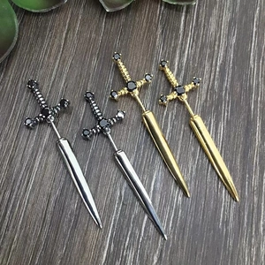Gothic sword stud earrings in gold and silver with black zircon on dark wood
