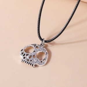 Macro detail of silver hollow skull pendant with textured finish and black rope chain