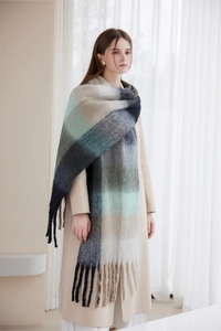 Close-up of a gradient plaid winter scarf featuring tassels on a beige coat