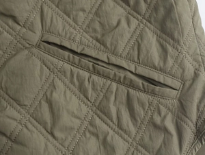 Détail de la veste vert olive avec matelassage en losange et coutures de poche renforcées
