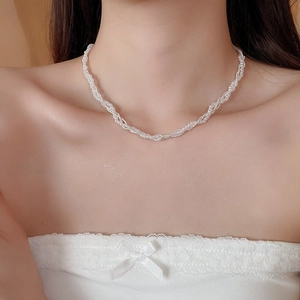 Close-up of triple-layered twisted pearl choker necklace on a woman's collarbone