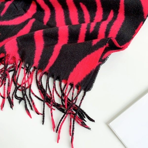 Detail of red and black striped knitted scarf featuring soft fringe and thick cashmere texture
