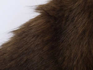 Texture détaillée de la fausse fourrure marron foncé sur cette veste pour femme