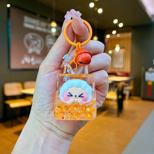 Handheld view of orange acrylic liquid keychain with star glitter and cartoon charm