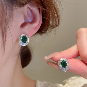 Close-up of green emerald zircon earrings showing sparkling vintage halo design details