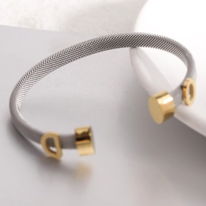 Detail of 6mm stainless steel cable wire cuff bracelet featuring golden D charm