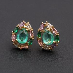 Macro detail of gold plated teardrop earrings with green and colorful zircon stones