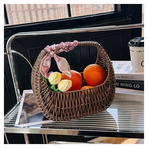 Detail of woven rattan basket handbag with floral silk scarf handle on glass table