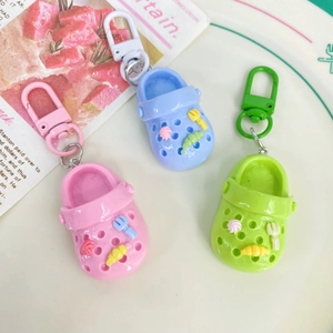 Close-up of pink, blue, and green mini clog shoe keychains arranged on a white plate