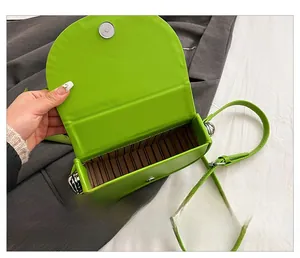 Detail view of green leather saddle bag featuring magnetic clasp and striped lining