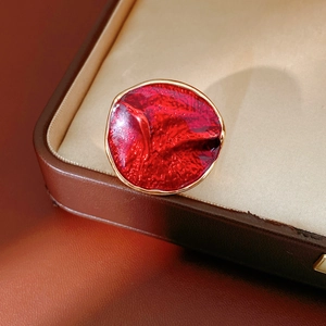 Macro shot of luxury red enamel ring in gold finish resting inside a brown leather jewelry box