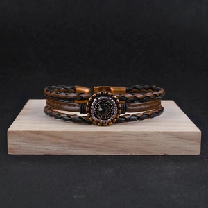 Close-up of vintage multilayer braided leather bracelet with central metal bead on wood