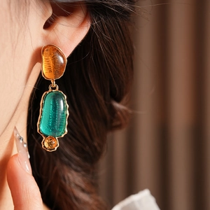 Detail of vintage oval resin earrings in amber and emerald green on model