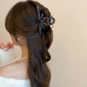 Detail view of large leopard print hair claw clip worn in a stylish bun hairstyle