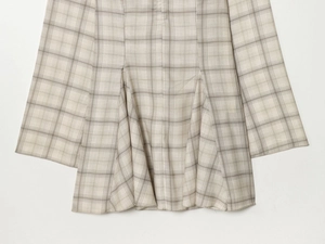 Detailed close-up of plaid fabric seam alignment and flared ruffle hem of the dress