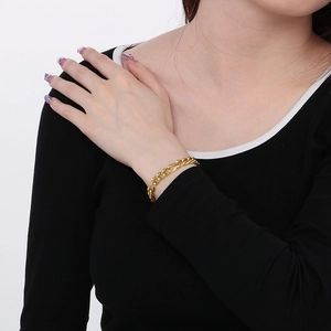 Close-up of a classic golden chain bracelet worn on a wrist against a clean white background