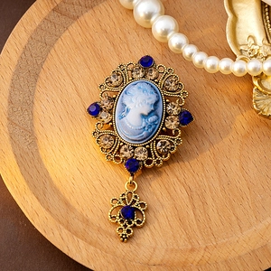 Vintage relief lady brooch with blue gems and golden filigree in a retro palace style